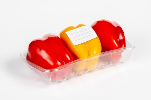 Package of red and yellow pepper with white label in isolated white background