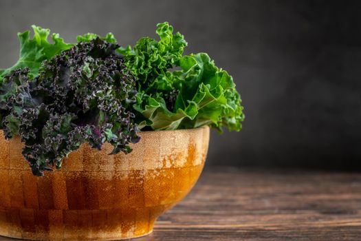 green leafy kale vegetable in bamboo bowl on wooden table background