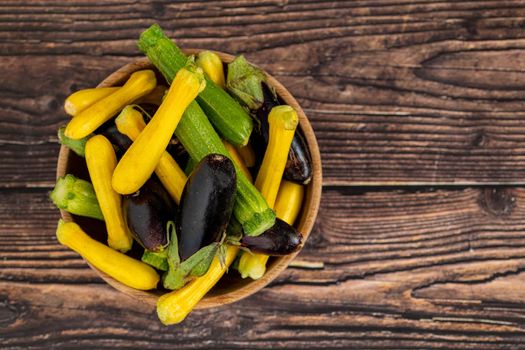 Baby Eggplant and zucchini in bamboo bowl on wooden table background