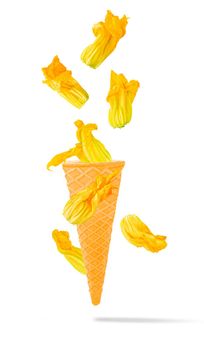 Isolated flying vegetables. Seven courgette flowers falling in ice cream waffle cone in motion with clipping path as package design element and advertising. Full depth of field.