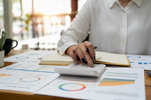 Finance and Investment, tax calculation and budget, Asian female entrepreneur using a calculator to calculate. Company business results document