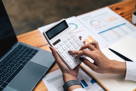 business woman or accountant working on calculator to calculate business data, accountancy document and laptop computer at office, business concept.