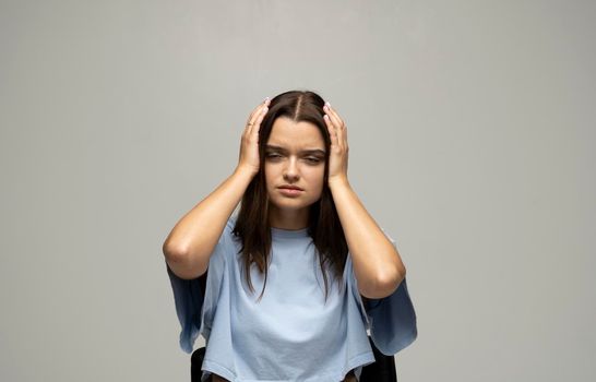 Portrait of stressed beautiful brunette woman holding her head with hands having headache. Attractive female suffering from head pain