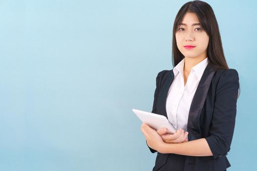 Young women standing in suit holding her digital tablet computor against blue background