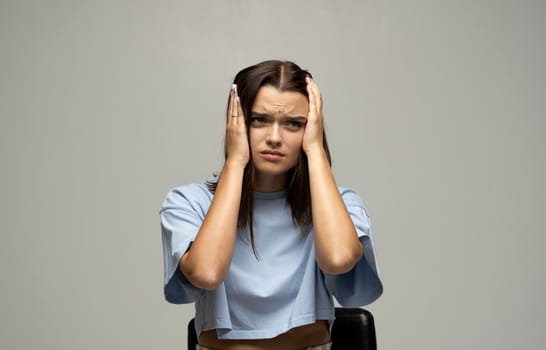 Portrait of stressed beautiful brunette woman holding her head with hands having headache. Attractive female suffering from head pain