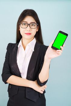 Young women in suit holding her  smartphone mock up green screen standing against blue background