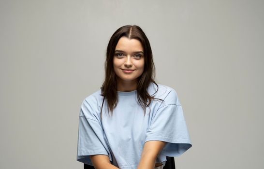 Portrait of young beautiful cute cheerful girl woman in beige t-shirt smiling looking at camera over blue background