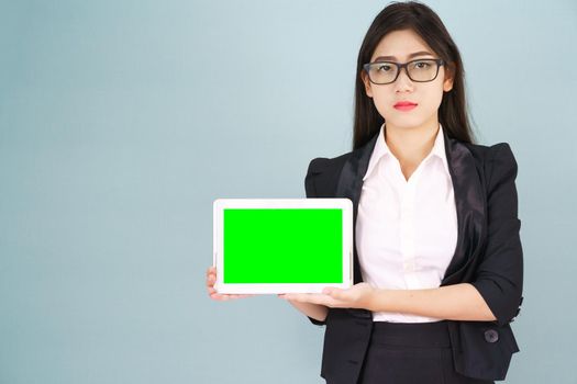 Young asian women in suit holding her digital tablet mock up standing against green background