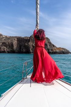 Attractive middle-aged woman in a red dress on a yacht on a summer day. Luxury summer adventure, outdoor activities