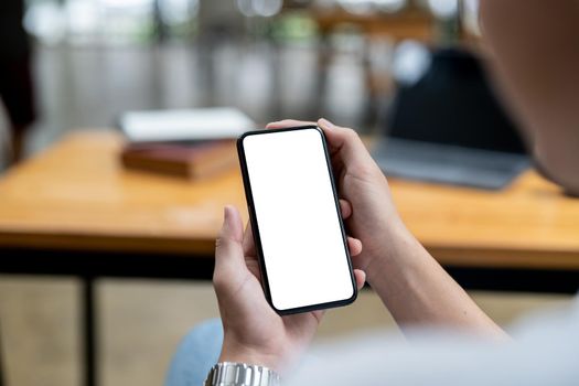 Mockup image of a woman holding black mobile phone with blank white screen while sitting in cafe
