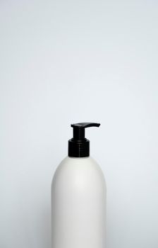 White cosmetic plastic bottle with black pump dispenser on white background. Liquid container for gel, lotion, cream, shampoo, bath foam