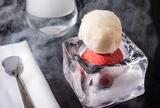 Strawberry and vanilla ice cream in ice bowl on black background.