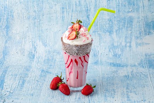 Refreshing strawberry milkshake on blue stone background