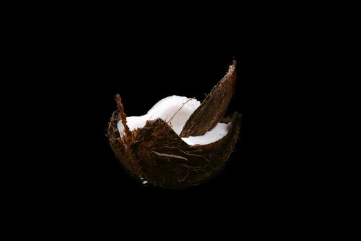 Coconut on a black background isolated. Broken coconut.