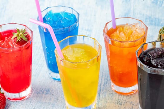 Refreshing frozens in various fruits and colors on a blue background.