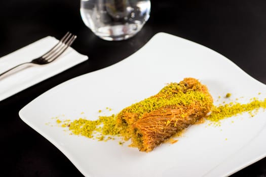 Kadayif dessert with pistachio on a white porcelain plate.