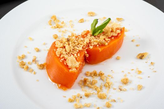 Pumpkin dessert with tahini and walnuts on a white porcelain plate