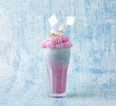 Blue and pink milkshake decorated with marshmallows on a blue background.