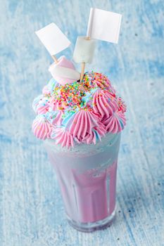 Blue and pink milkshake decorated with marshmallows on a blue background.