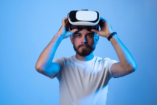 Portrait of young bearded man ready for wearing VR headset to watch 3d virtual video with AR experience. Future of online streaming in metaverse