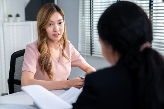 A young female asian candidate tries to impress her interviewer by being competent. International company, multicultural environment in workplace.