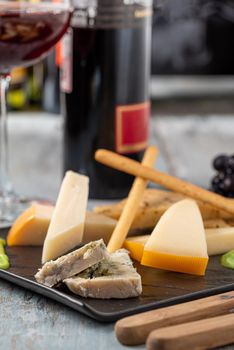Cheese plate served with grapes, strawberry, crackers and nuts on a wooden background