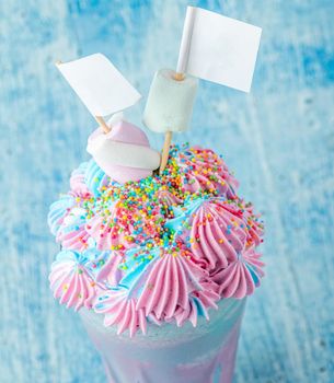 Blue and pink milkshake decorated with marshmallows on a blue background.