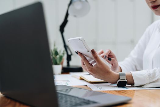 business woman or accountant working on calculator to calculate business data, accountancy document and laptop computer at office, business concept.