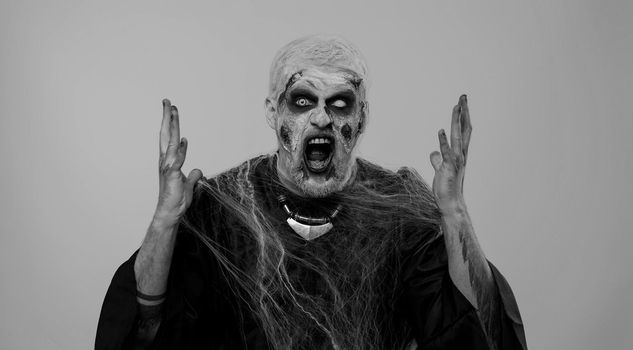 Dissatisfied frightening man with Halloween zombie bloody wounded makeup asking reason of failure, expressing disbelief irritation, feeling bored, disappointed in result, bad news. Sinister undead guy