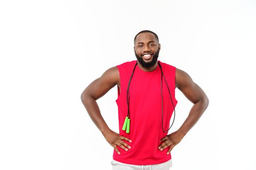 African fitness model with skipping rope against grey background. Handsome muscular man posing with jumping rope