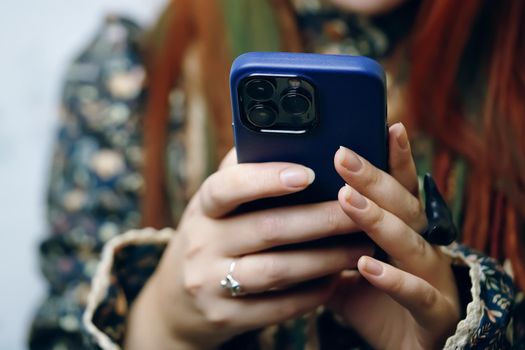 Woman blogger holds iPhone 13 pro in blue case and looks at screen. Smartphone in female's hands. Photos for advertising apps and gadgets. Bishkek, Kyrgyzstan - January 24, 2022