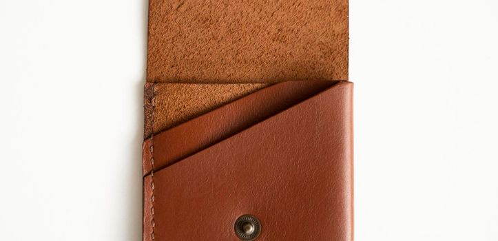 Opened empty orange genuine leather card holder on a white surface