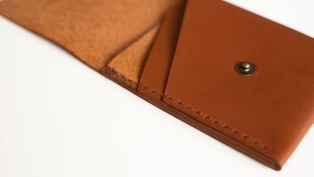 Opened empty orange genuine leather card holder on a white surface