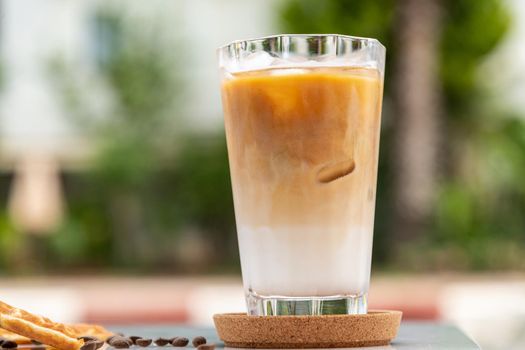 A cup of Iced Latte Coffee with ice cubes placed on a marble table in a coffee shop.