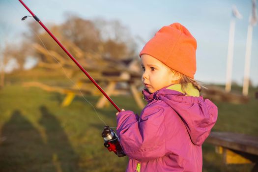 Charming baby fishing in the river at sunset.