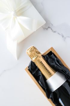 Wedding celebration, lifestyle and luxury present concept - A champagne bottle and a gift box on marble