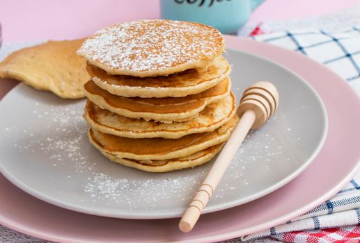 homemade banana pancakes on plate sprinkled powder and honey. Pancakes on the kitchen table against the background of eggs and cups with coffee. Pancake slide with honey topping and fresh bananas