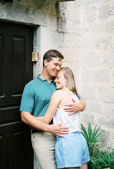 Man hugging a woman near the door of a stone building. High quality photo