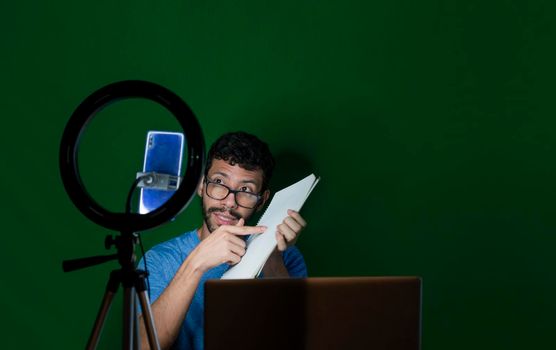 Man giving classes in a video call. Online classes concept. Man giving online classes with phone. Guy with laptop making video blog on phone. Guy on a video call working from home