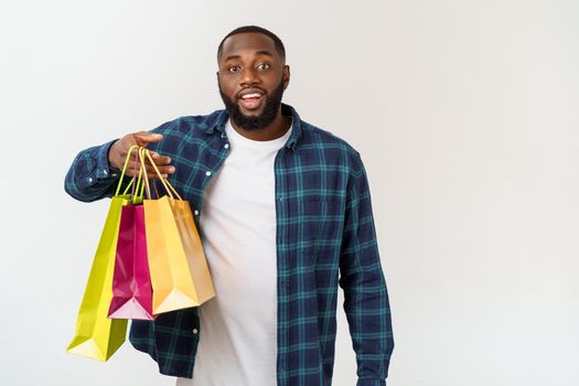 Happy african american man holding shopping bags on white background. Holidays concept.