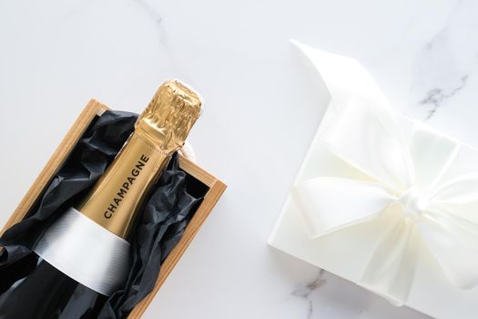 Wedding celebration, lifestyle and luxury present concept - A champagne bottle and a gift box on marble