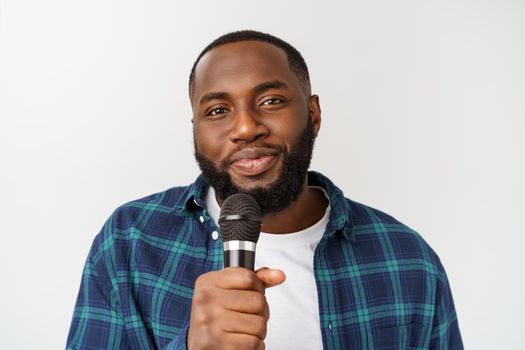 Portrait of cheerful positive chic handsome african man holding microphone singing song. Isolated on white background