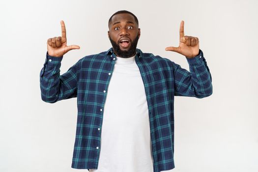 Young amazed African American pointing his finger at white background with copy space for your advertisement.