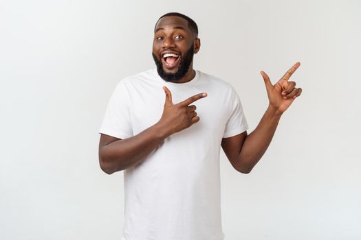 Young amazed African American pointing his finger at white background with copy space for your advertisement.