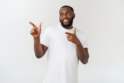 Young amazed African American pointing his finger at white background with copy space for your advertisement.