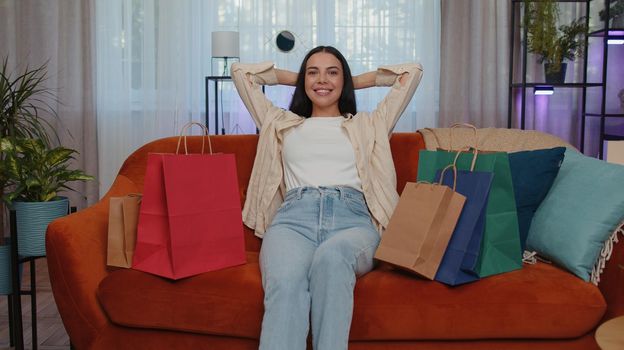 Portrait of caucasian adult girl happy shopaholic consumer came back home after shopping sale with bags. Young woman satisfied received parcels from online order at modern home apartment living room