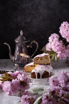 Easter cake and painted eggs and a bouquet of pink sakura flowers on a table in a decorated spring room, a beautiful still life. High quality photo