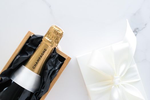 Wedding celebration, lifestyle and luxury present concept - A champagne bottle and a gift box on marble