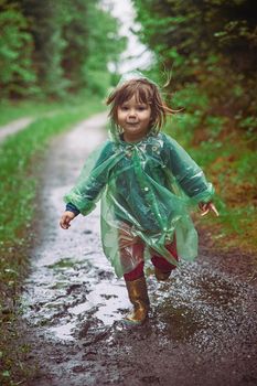 Charming child in a raincoat in the evening forest in Denmark