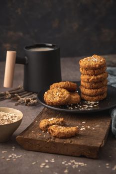 Homemade oatmeal raisin cookies with cup of cappuccino on rustic background.